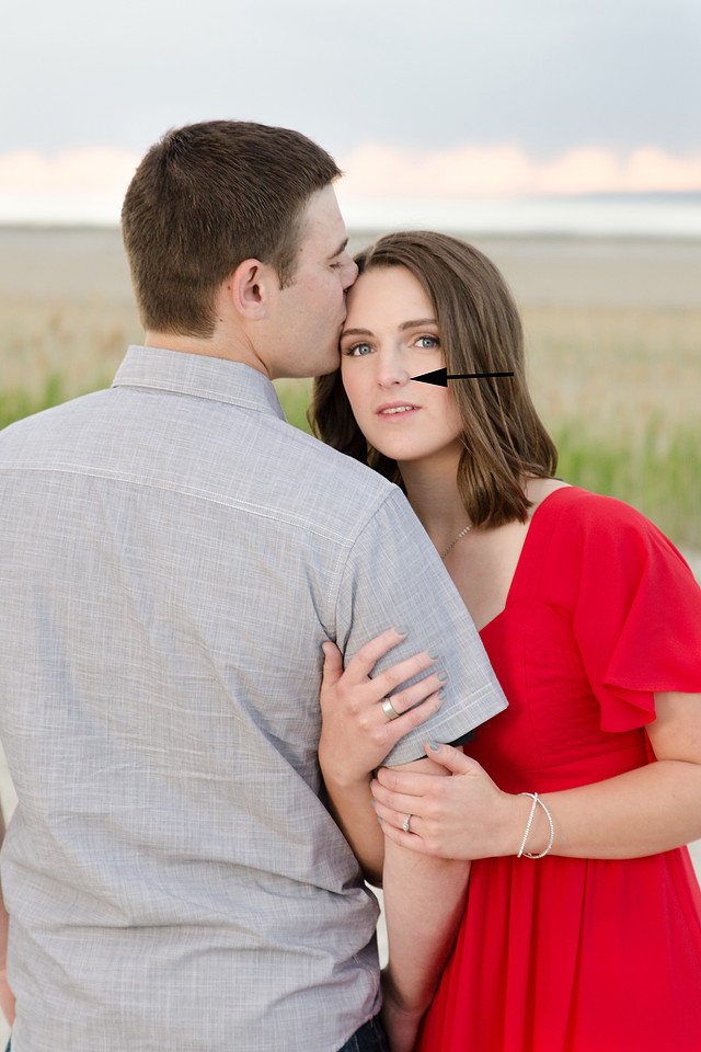 engagement picture of bride in red dress snuggled against groom who is kissing her forehead. Image from Skylight Studio photography in Brenham Texas
