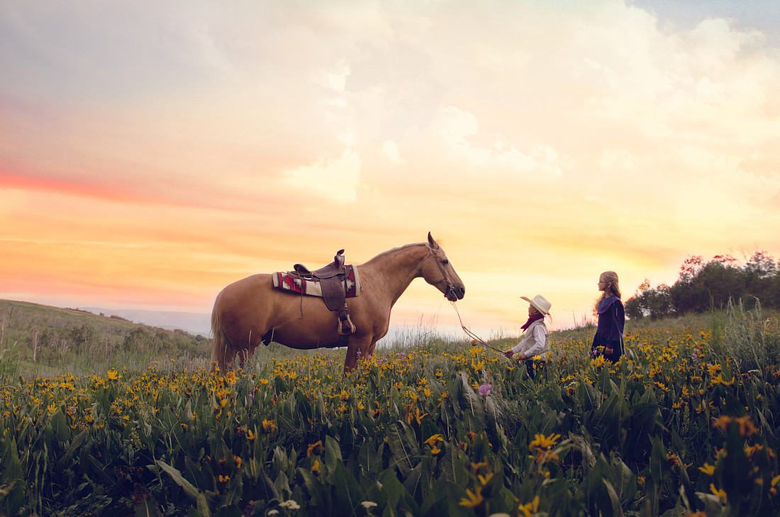 young boy aabd girl with a horse in the wildflowers in a vintage western style children's session taken by Skylight Studio out of Pocatello Idaho