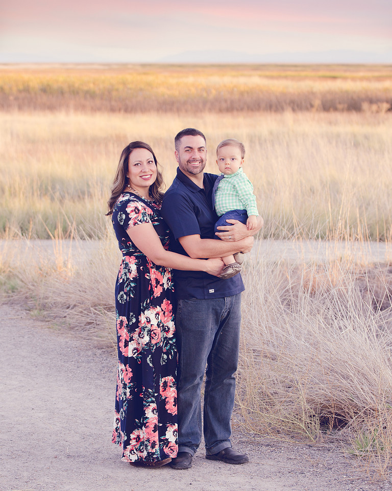 Family portrait of a mom, dad, and baby boy taken at dusk in a tall grassy field by Skylight Studio based out of Pocatello  Idaho